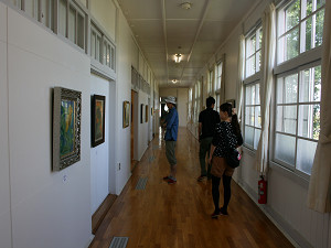 廊下に飾られた絵画を鑑賞する様子の写真